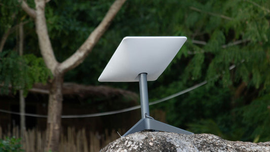 White satellite dish on a stand on rocks.